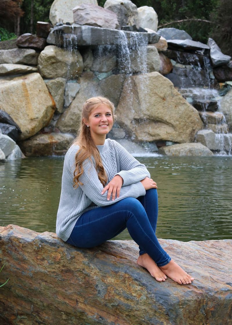 A young woman sitting on a rock beside the waterfall pool