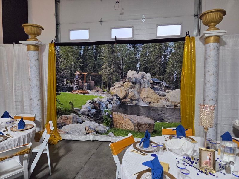 An indoor reception set with a waterfall backdrop and gold columns